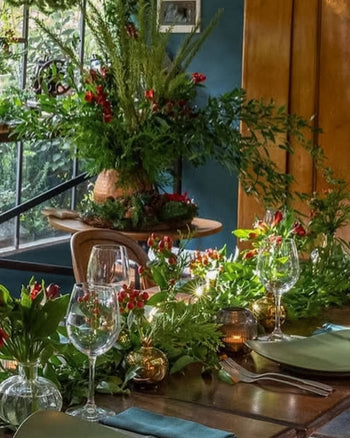 Antonia Flowers Roma, allestimento botanico indoor con tulipani rossi, verde naturale, candele e mise en place elegante