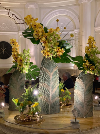 Allestimento floreale in lobby con orchidee gialle, verdi tropicali e vasi scultorei