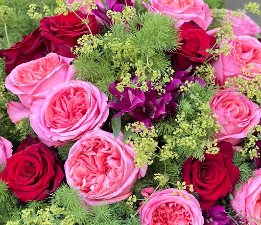 Dettaglio di composizione floreale con rose inglesi rosa e rosse e verde ornamentale
