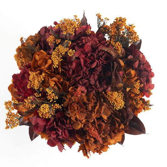 Composizione Florever Amber Sunrise con ortensie e fiori stabilizzati nei toni bordeaux, ambra e arancio vista dall'alto.