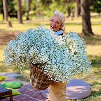 Fiorista con grande cesto di gypsophila bianca durante un allestimento all’aperto