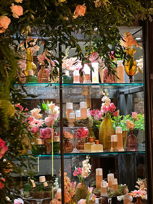Scenografia floreale per Laura Biagiotti con composizioni rosa, verdi e vasi decorativi su struttura espositiva