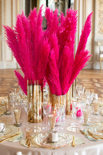 Allestimento floreale con pampas fucsia in vasi dorati per tavolo evento
