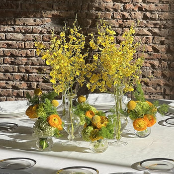 llestimento floreale da tavolo nei toni giallo e verde con fiori in vasi di vetro