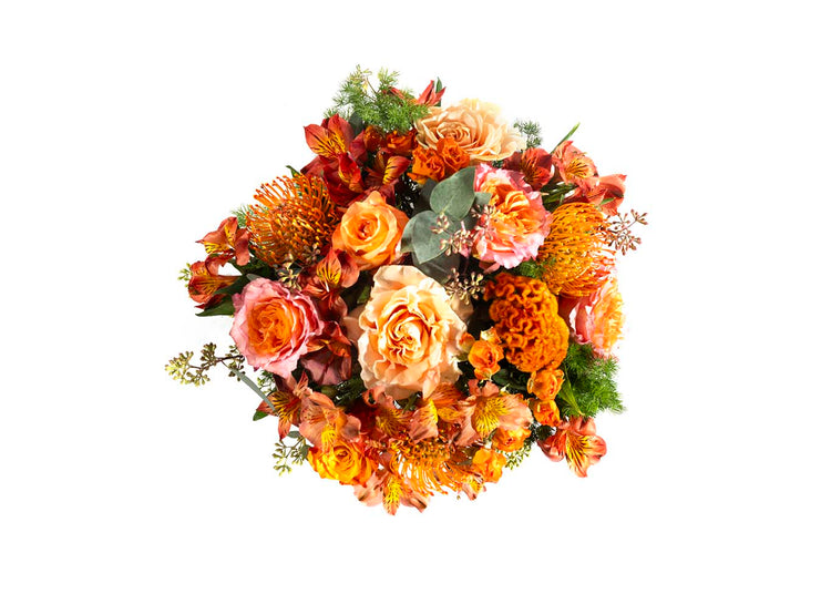 Composizione floreale Ortigia nei toni arancio e pesca con rose, celosia, alstroemeria ed eucalipto, vista dall’alto