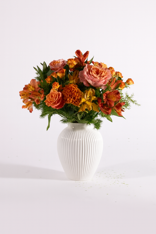 Bouquet autunnale nei toni arancio, rosa e verde con rose e fiori stagionali in vaso bianco